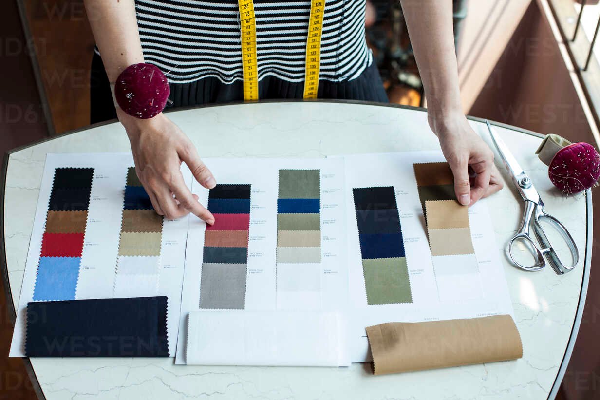 High angle close up of fashion designer working in her studio, looking at fabric samples.
